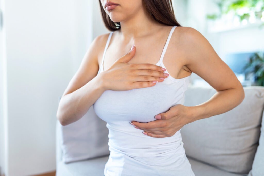 Young woman feeling her breast implants for signs of complications