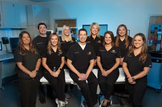 surgical team in black scrubs posing in operating room at Little Rock cosmetic surgeon's office