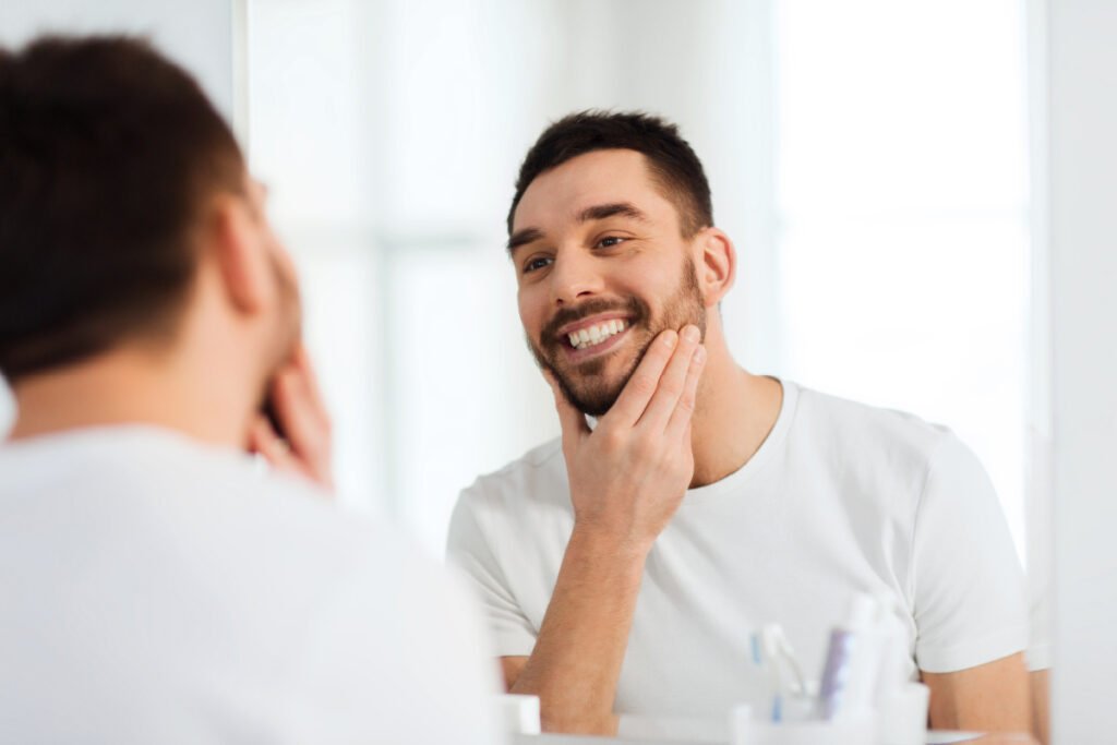 Man touching face smiling in mirror