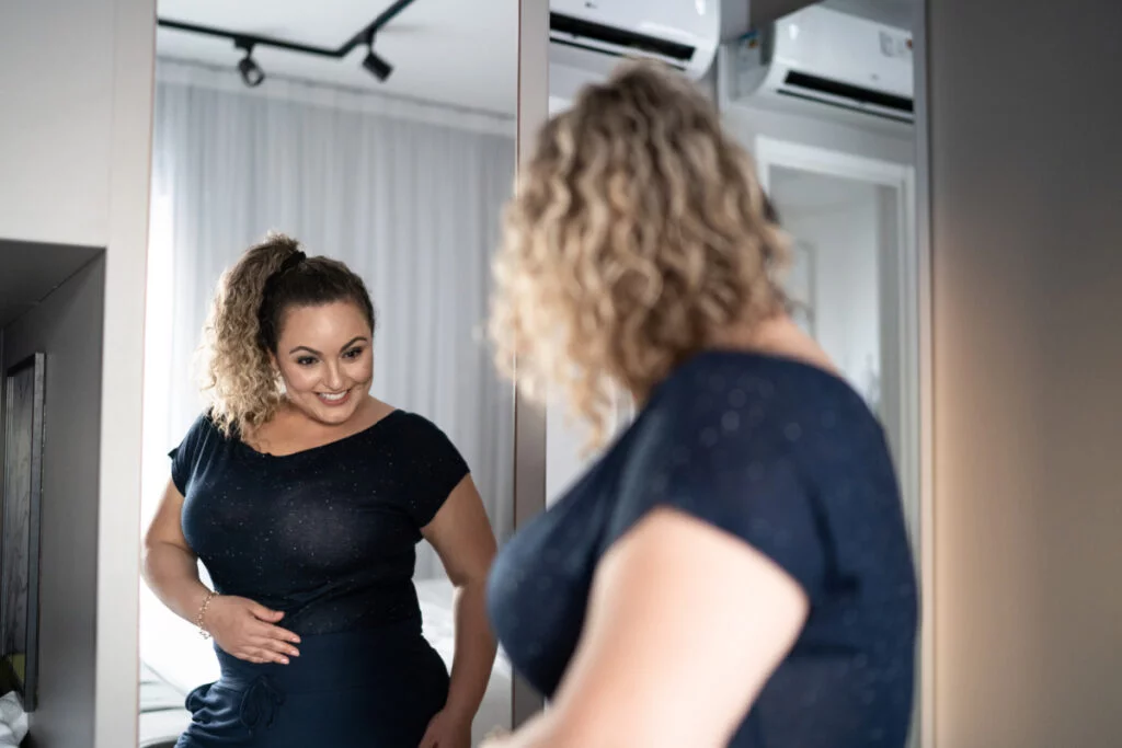 Woman looking in mirror seeing results from semaglutide injections