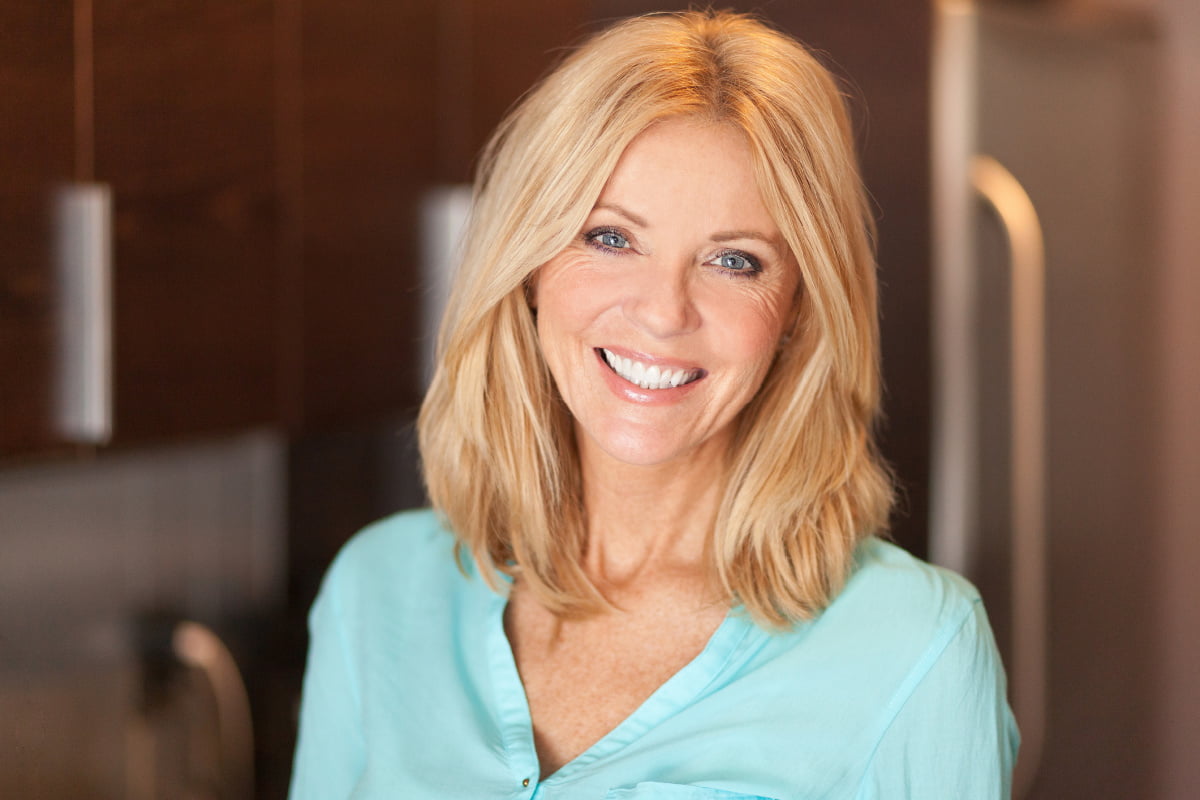 Mature blonde woman with blue eyes smiling at the camera