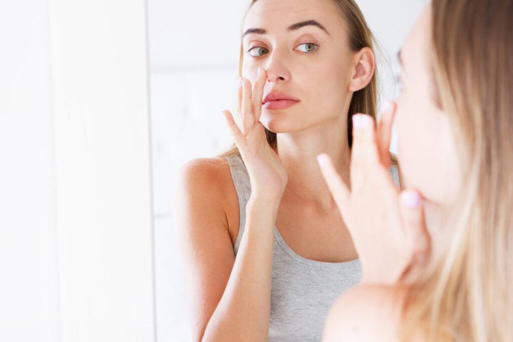 Young woman touching skin in mirror