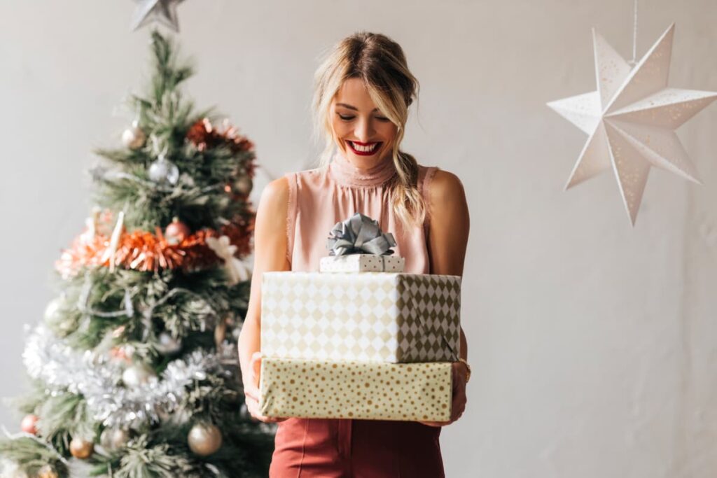 Woman holding presents by a Christmas tree